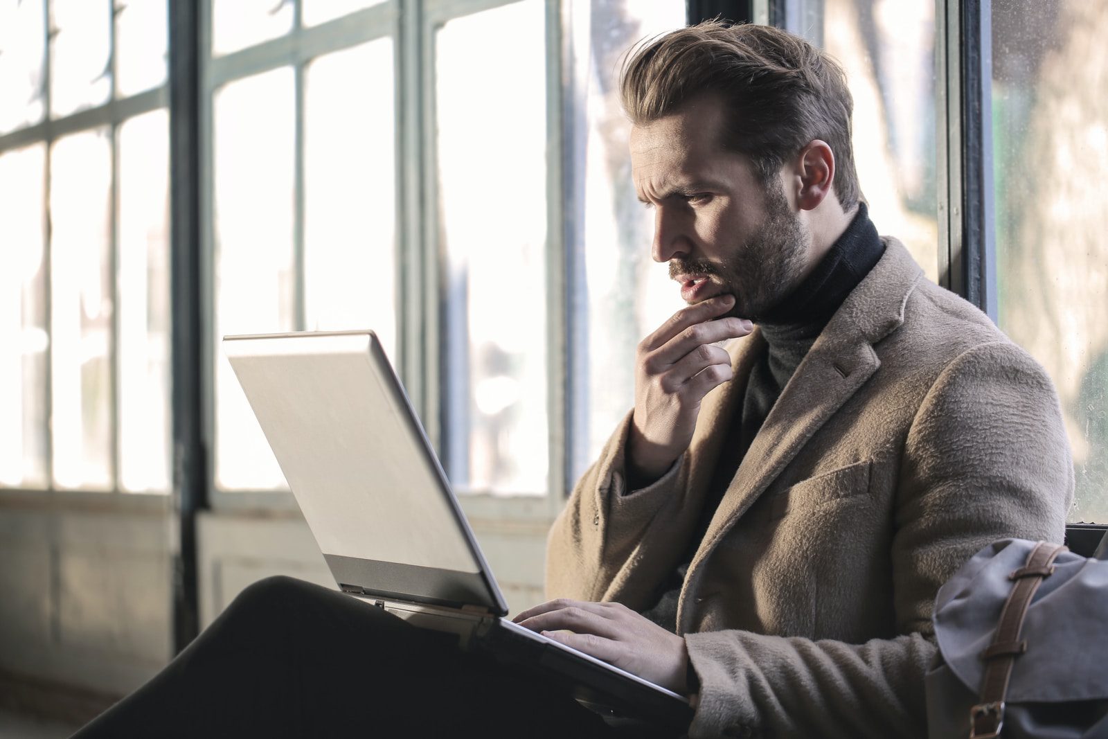 Man holding his chin, looking at laptop screen in question.